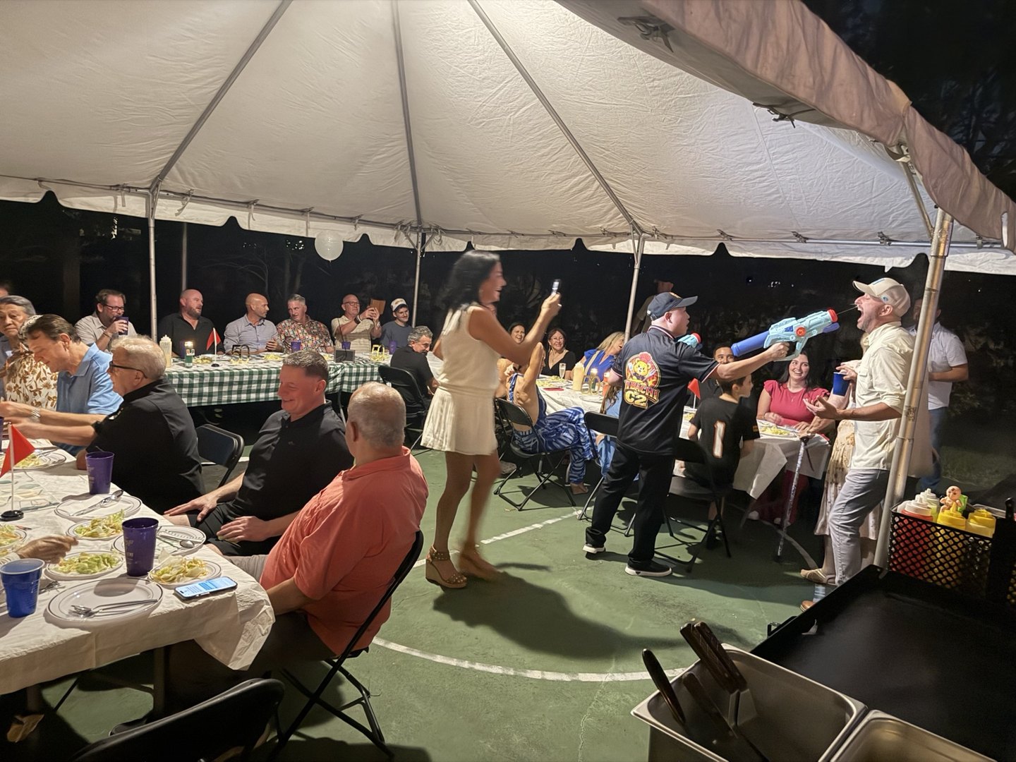 Guests gathered under a backyard tent while a Hibachi C2 chef entertains the party