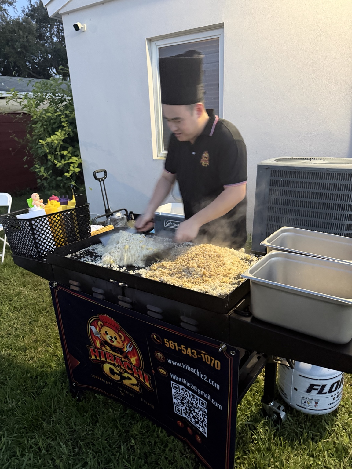 Hibachi C2 chef cooking fried rice at a branded mobile grill in a backyard